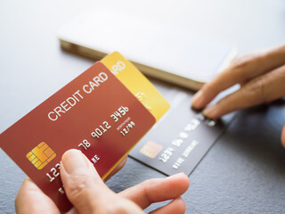 Finger holding Credit card with blur Smartphone on black wooden table background,Technology Electronic Ecommerce Shopping Online,Plan Investment Income for 2023 New Year. Business and Finance concept.