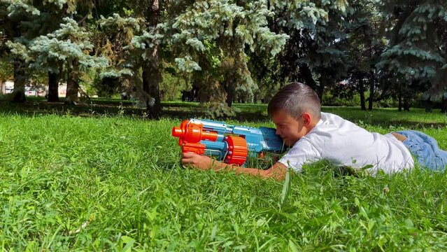 A boy playing with his nerf gun at the park. 