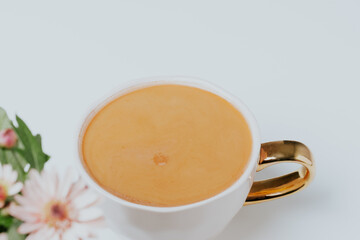 Beautiful blurred view to white cup with coffee and pink chrysanthemums in pot. Light background. Place for your text.