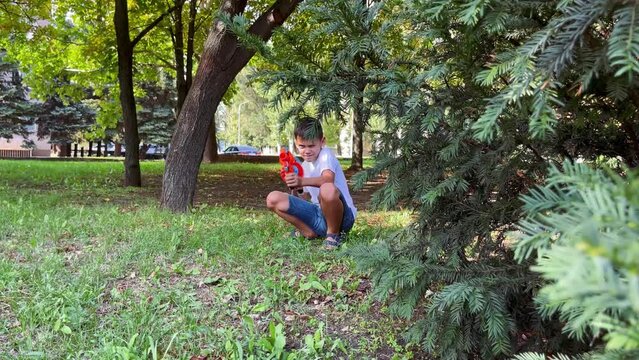 A boy playing with his nerf gun at the park. 