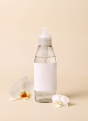 Obraz na płótnie Canvas Cosmetic pump dispenser bottle near white orchid flowers on light beige close up. Mockup