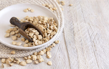 Scoop of raw dry Grass pea close up on wooden table. Legumes known in Italy as Cicerchia
