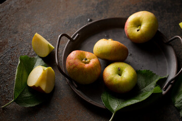 Small apples on a metal tray on a dark background