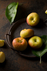 Small flattened apples on a tray on a dark background