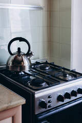 The kettle is on the gas stove in the kitchen