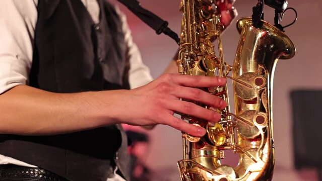 Musician playing saxophone, close-up of hands and saxophone