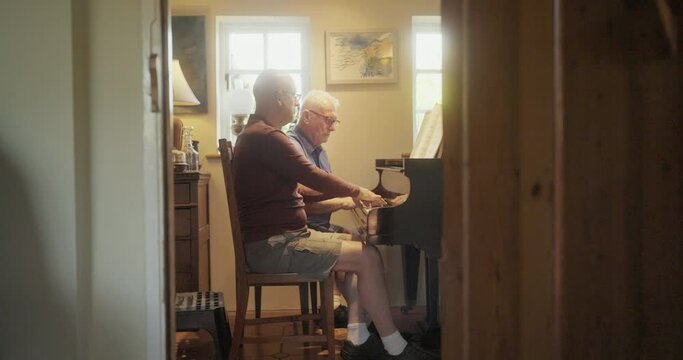 WS Senior gay couple playing piano at home / East Sussex, UK