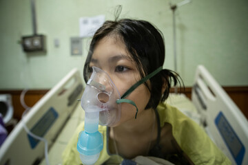 Close up sick Yong asian girl with face oxygen mask,on bed in hospital, Healthcare workers in the...