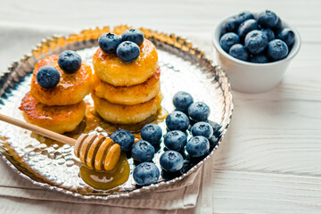 Homemade cheesecake with freshly picked juicy blueberries in the plate on wooden background, close up. Blueberries background. Concept of healthy nutrition, organic food, breakfast
