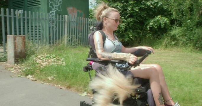 MS TS Smiling woman in motorized wheelchair with dog in park / Sheffield, UK