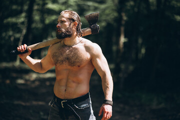 Lumberjack with an axe standing naked in forest