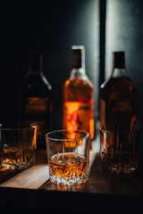 bottle and glass of whiskey with ice on a wooden background