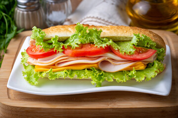 Cheese, ham, lettuce and tomato slices in an appetizing tasty sandwich.