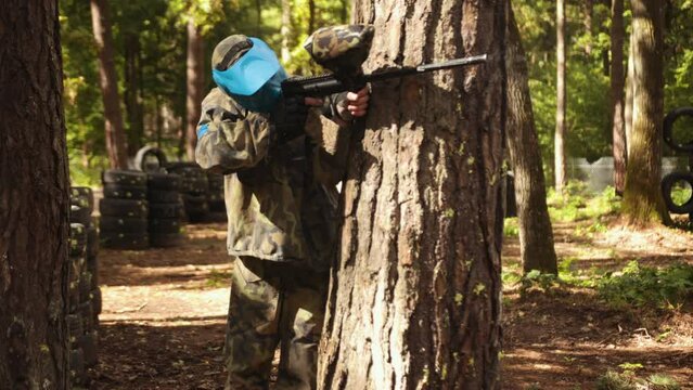 Playing paintball battle with friends, wearing camouflage and protective masks, engage in leisure activity, adrenaline-fueled sport, play a paintball game outdoors