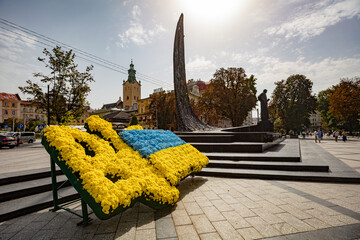 Flowerbed in form of Ukraine national emblem and flag near Taras Shevchenko monument in Lviv - obrazy, fototapety, plakaty
