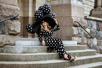 Spring, summer fashion. Glamour, stylish elegant woman in polka dot jumpsuit and big hat is holding...