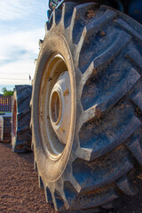 Big rubber wheels of soil grade tractor car earthmoving at road construction side. Close-up of a dirty loader wheel with a large tread
