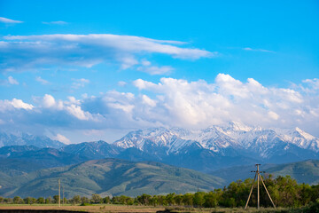 Fantastic landscape, mountains with lush clouds and a fertile valley in front of them.
