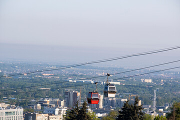 Two funicular cabins against the backdrop of the city of Almaty.