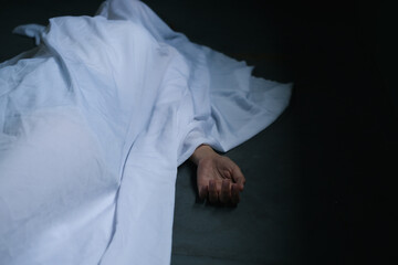 Dead woman lying down under white cloth covered death body from  murder at house of victim, Horror and crime scene.