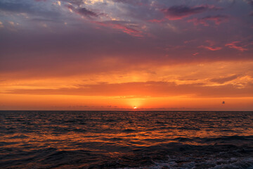 Naklejka na ściany i meble Beautiful sunset over the sea with bright orange clouds.