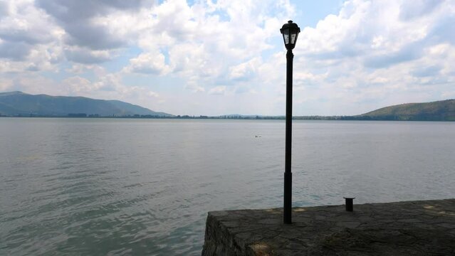 Street lamp in the shore of Lake Orestiada against mountains in Greece