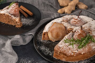Delicious spice cake with pear, ginger and cinnamon on a dark kitchen counter.