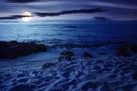 night scenery at the sea. calm waves washing the sandy beach in full moon light. transparent water and bright blue sky