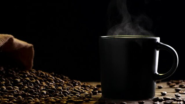 Hot Coffee Cup Concept. Close-up black coffee cup, mug with beautiful steaming smoke, classic vintage coffee grinder espresso manual, beans, burlap on on old wooden table dark, black background. Hot D