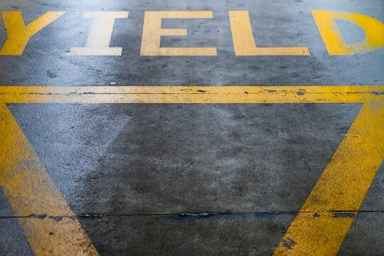 Yellow yield sign at the exit of a car park