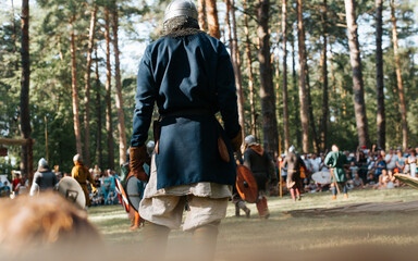 Costumed reconstruction of medieval battle in open air. Back view of viking warrior in helmet...
