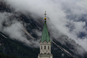 The bell tower of Cortina d'Ampezzo surrounded by clouds 