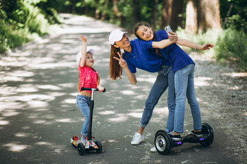 Mother with daughters on scooter having fun in park