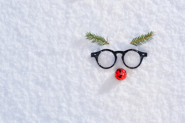 Face made on white snow by glasses, glass ball, Christmas tree twigs. Merry Christmas and Happy New...