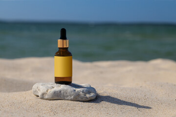 A natural mock-up for a cosmetic product, a bottle with a dropper on a beach background. Space for text, blank label.