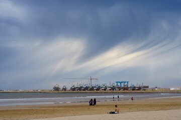 Essaouira beach with a port in the background under a stunning cloudy sky
