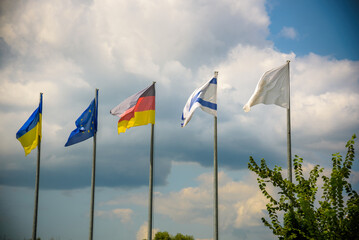 The flag of the European Union and flags of Ukraine, Israel, Germany flutter in the wind in different directions against the blue sky. Bottom side view - obrazy, fototapety, plakaty