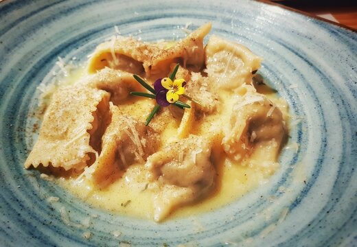 Closeup shot of a cappellacci plate with natural flower decoration on it