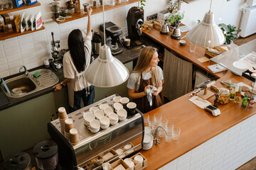 White two barista women smiling while working together in cafe