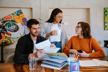 Multiracial young colleagues discussing project while working in office