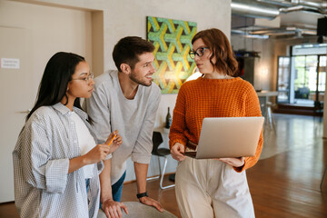 Multiracial young colleagues discussing project while working in office