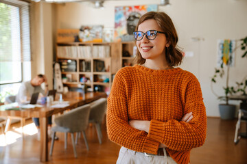 White ginger woman in eyeglasses smiling while working at office