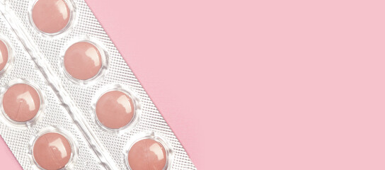 Blister de pastillas mediamentos rosas sobre fondo rosa pastel liso y aisado. Vista superior y de...