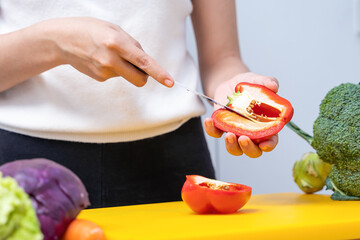 Young woman cutting vegetables in the kitchen. Woman's hands cutting vegetables, behind fresh vegetables. asian woman uses a knife and cooks.