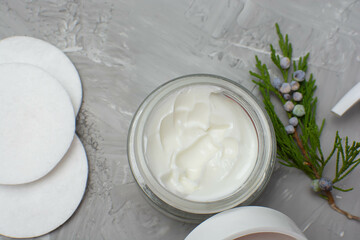Natural cosmetics concept, Top view photo of open white jar and green twig on gray background