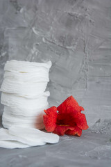 Cotton pads on a gray background, a red flower on a gray background, the concept of skin cleansing, cosmetics, eco cosmetics, skin care