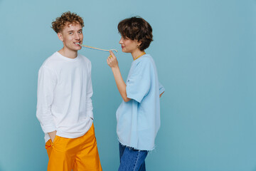 Young beautiful short-haired woman pulling candy from her boyfriend mouth