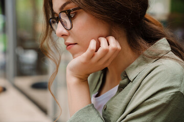 Portrait of young beautiful thoughtful woman in glasses propping head