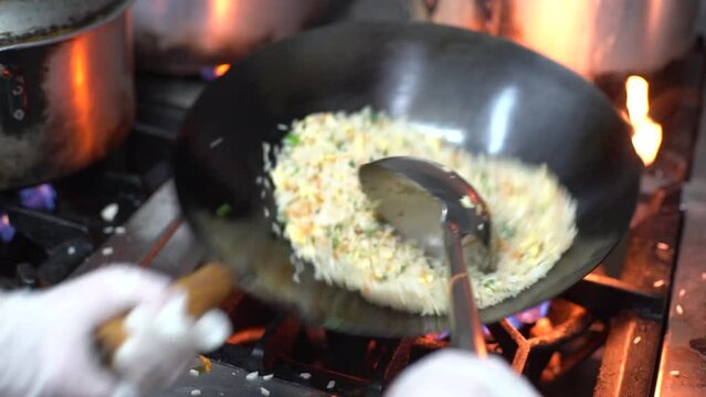 Cook preparing chow fan in the wok in the kitchen of an Asian restaurant