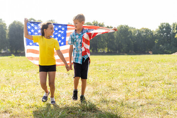 Children sit with American flag outdoors.